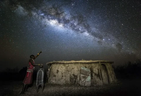 a masai man with his son under the stars