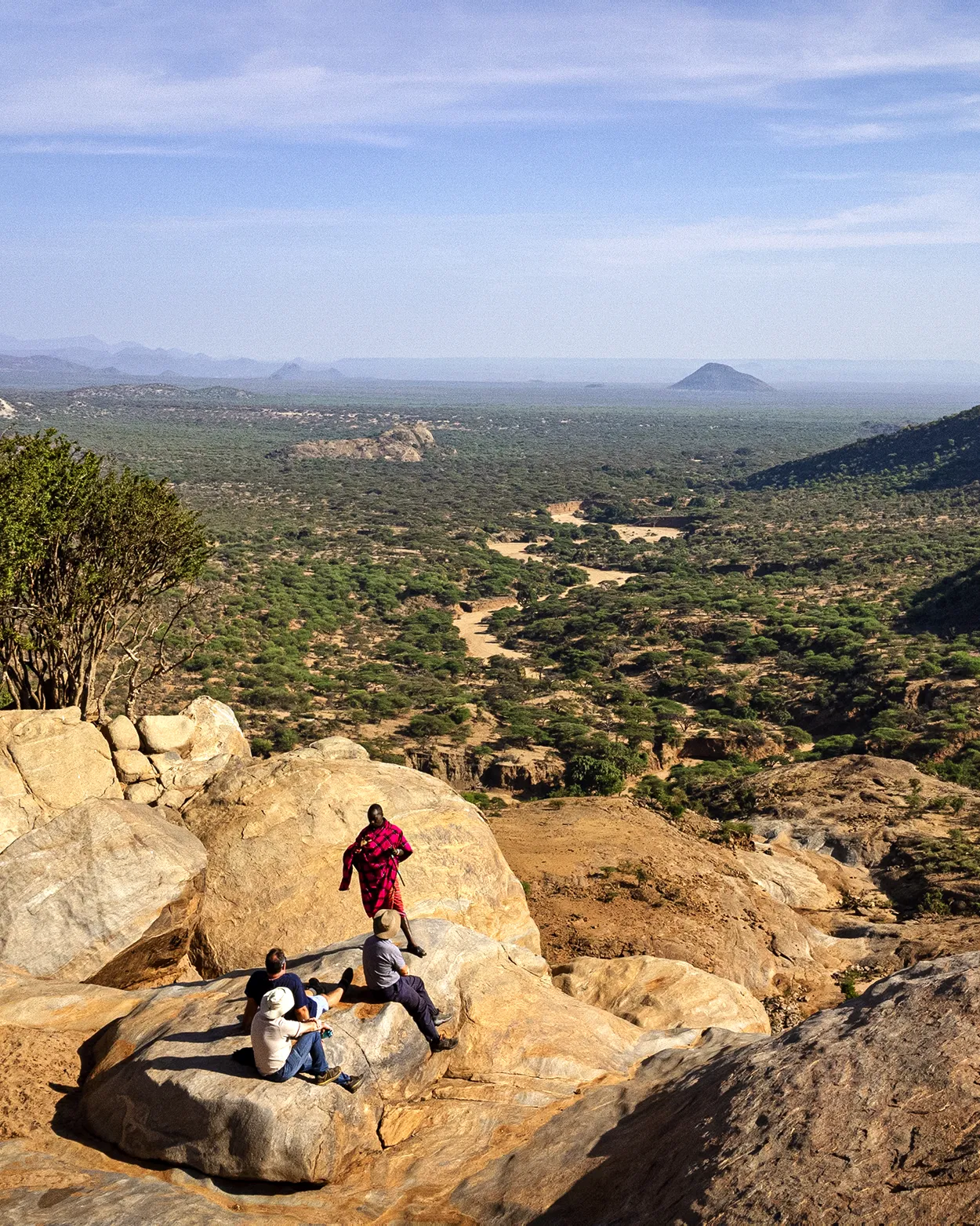 people seated on a rock with a view of Laikipia
